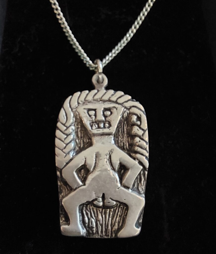 Sheela na Gig pendant and chain on black velvet background, featuring the Rahara Sheela