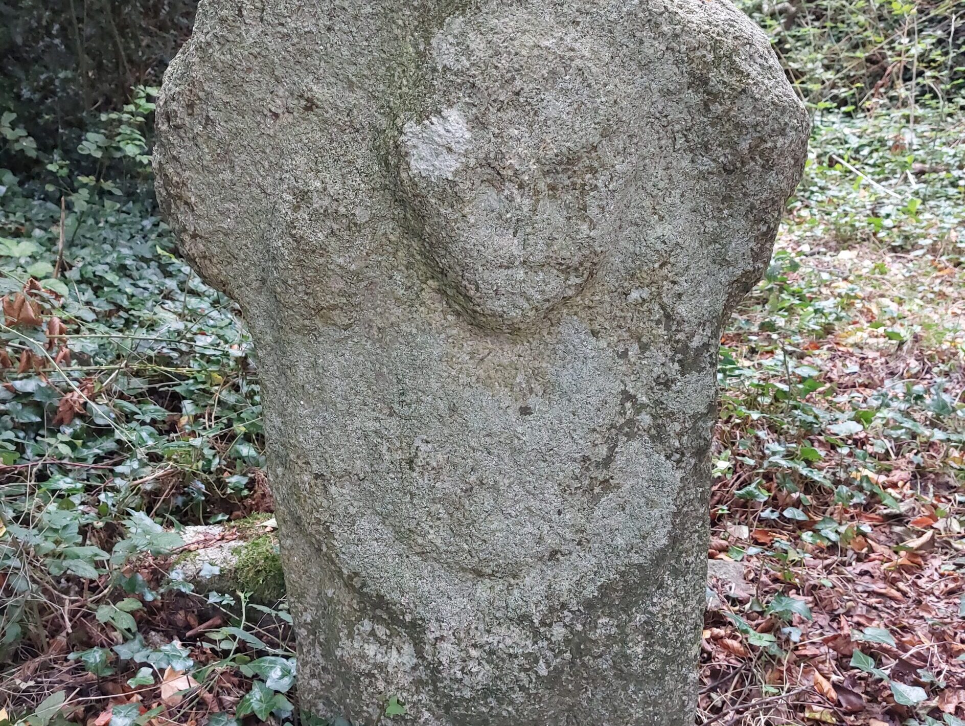A stone figure on a cross-shaped grave marker, thought to be a Sheela na Gig but more likely a later decorative feature