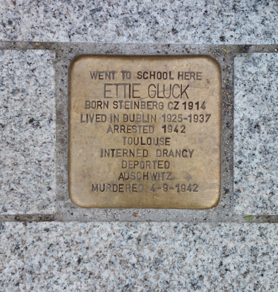 Small bronze plaque on pavement, called a Stoperstein, in memory of Holocaust victim Ettie Gluck née Steinberg 1914-1942. 
