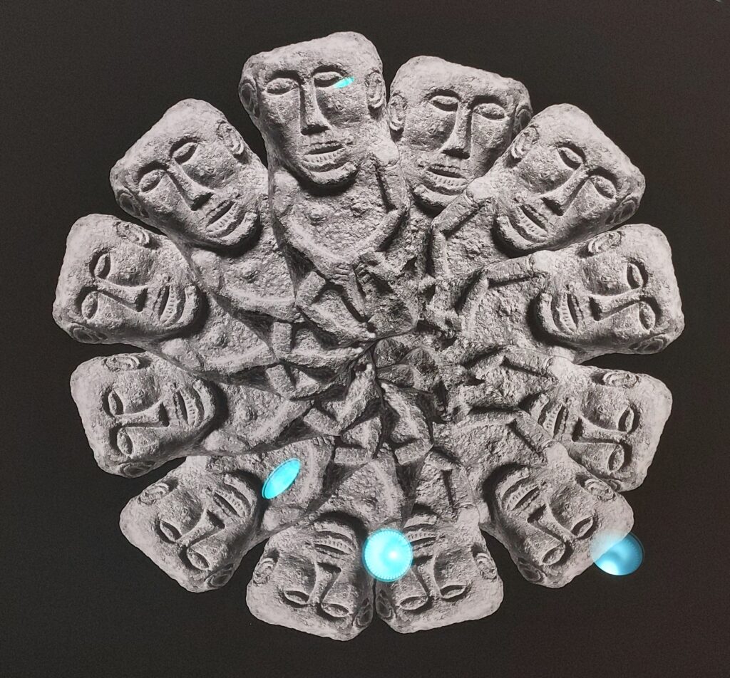 A stone circle with twelve faces of a Sheela na Gig type figure, joined in the centre with interlocking vulvas
