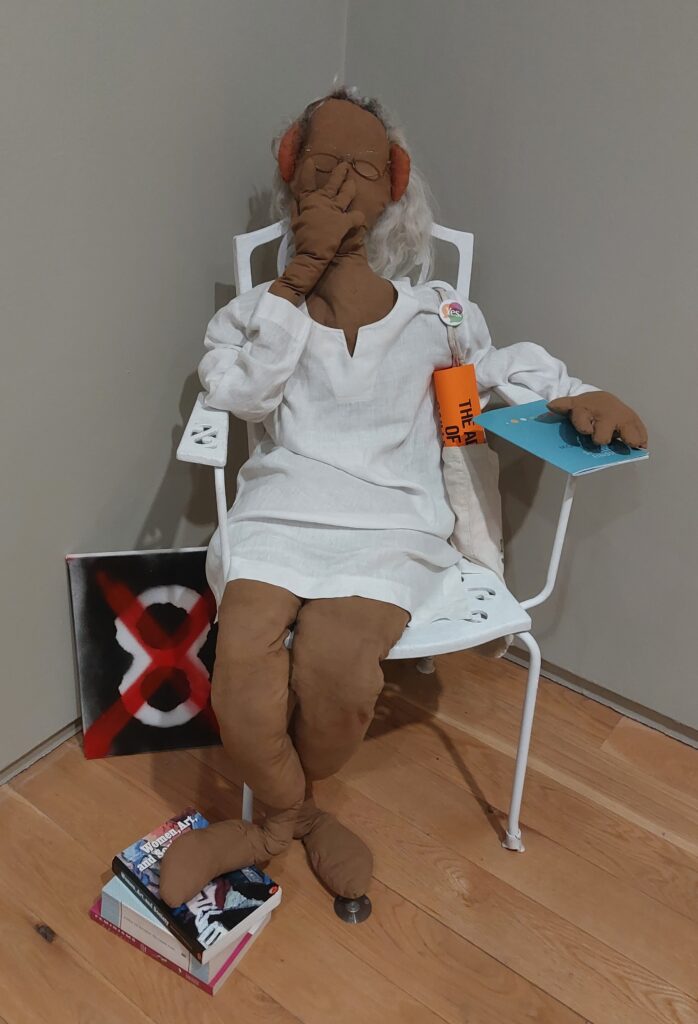 A stuffed fabric 'doll' of a female figure sitting in a chair with symbols from the Repeal the 8th campaign by artists Na Cailleache