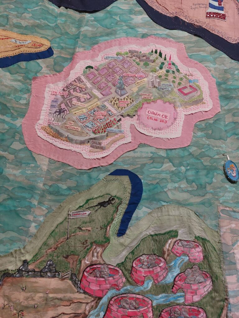 Oileán Olc, or Slag Island, a pink island embroidered on a blue sea of fabric, a detail from The Map by artists Alice Maher and Rachel Fallon