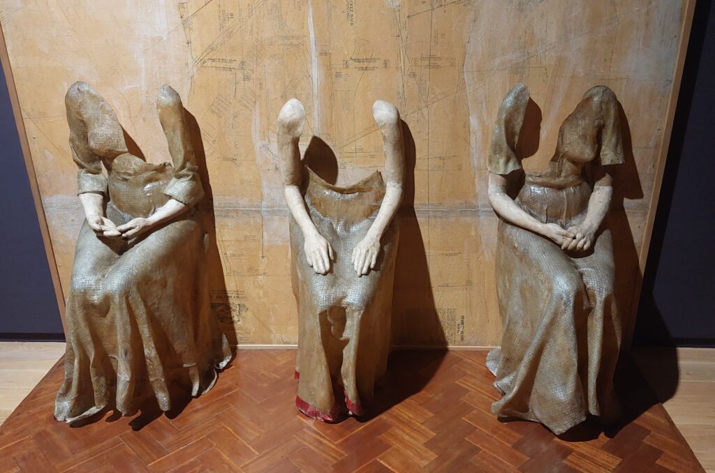 Waiting by artist Kathy Prendergast features three female figures, each missing a head and part of the torso as they passively sit, waiting to be asked to dance, and a parquet floor