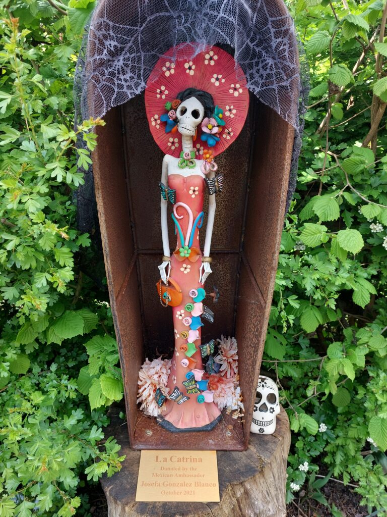 Mexican Day of the Dead statue of a female skeleton decorated with bright colours and a hat