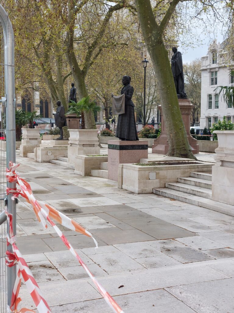 Statue of Millicent Fawcett in Parliament Square, London from a distance, surrounded by police tape