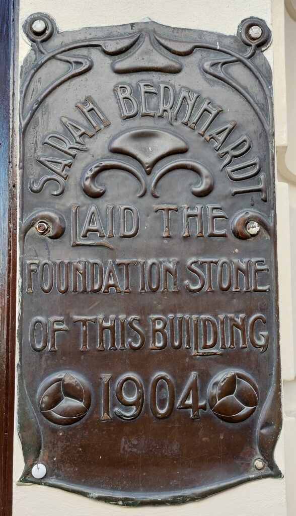 Ornate bronze plaque withe text: Sarah Bernhardt laid the foundation stone of this building 1904