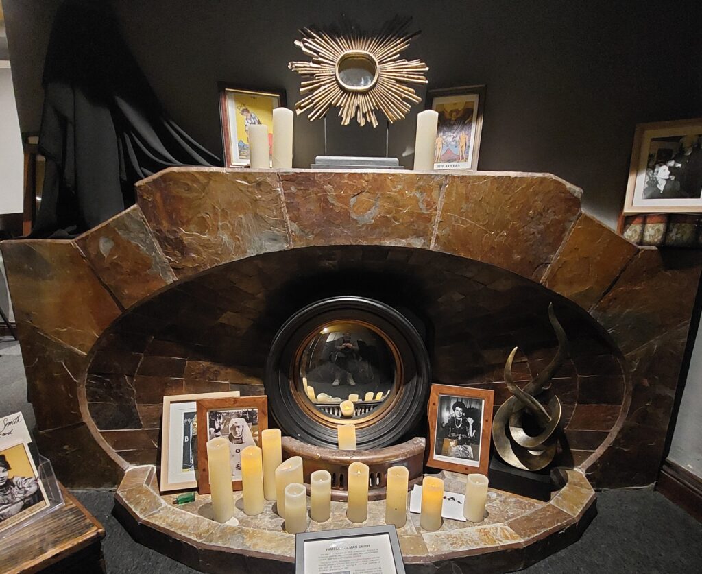 A curved art deco fireplace surrounded by candles, with a circular mirror at its centre